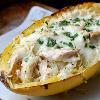 Gluten-free Chicken Alfredo Spaghetti Squash Boats served hot, garnished with fresh parsley for a colorful, healthy dinner.