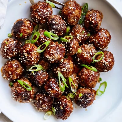 Tray of baked Firecracker Meatballs piled on rice, spicy sweet aroma rising